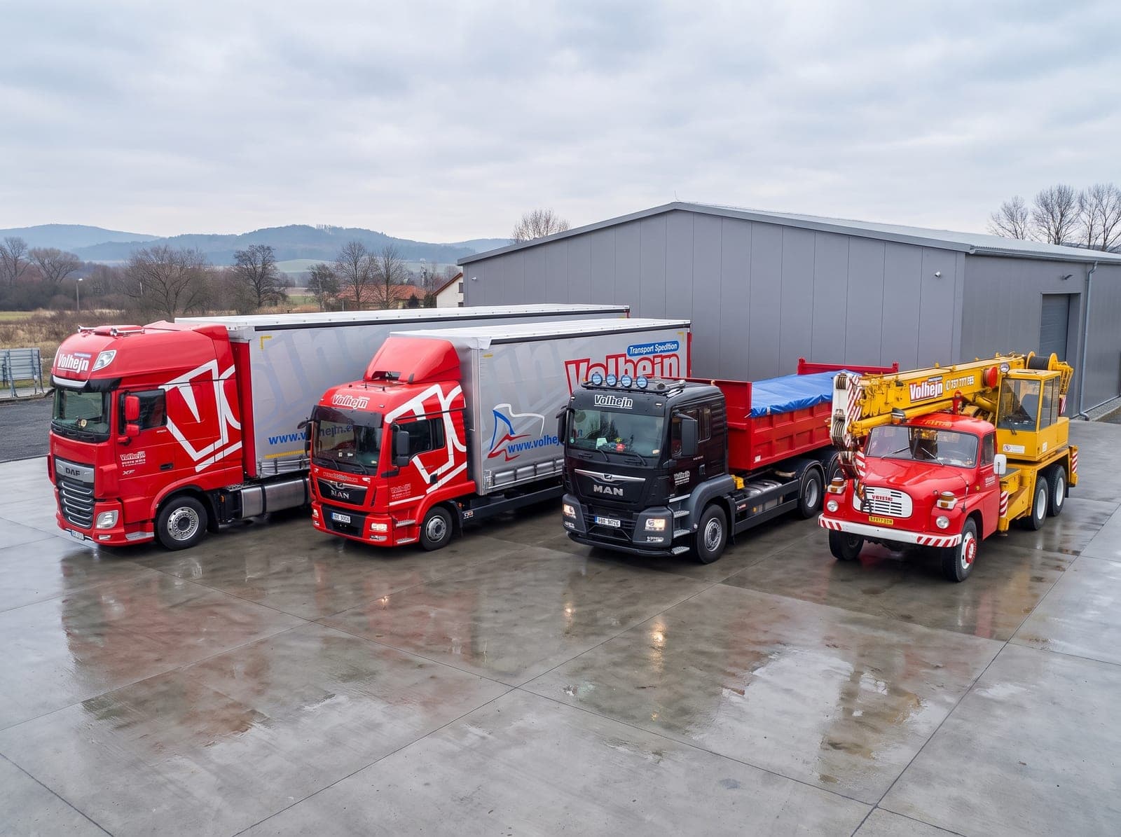 Souprava DAF XF, nákladní vůz MAN TGL, hákový nosič MAN TGS a autojeřáb Tatra AD 20 na firemním dvoře